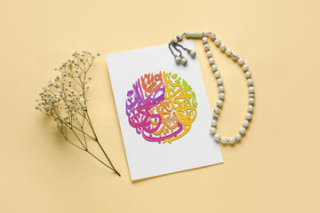 Paper with Arabic text, flowers and tasbih on color background