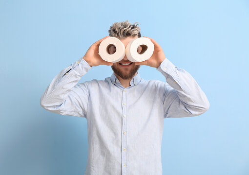 Funny young man with toilet paper on color background