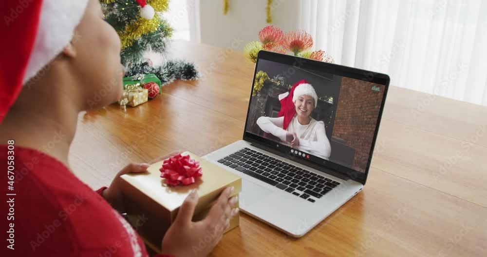 Poster African american woman with santa hat using laptop for christmas video call, with woman on screen