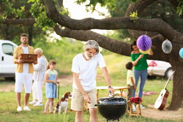 Senior man cooking food for barbecue party outdoors