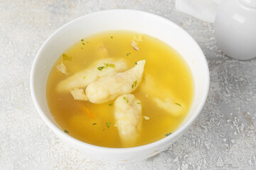 Bowl with delicious dumpling soup on light background