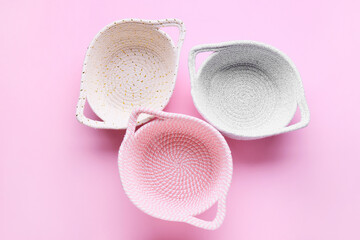 Stylish knitted baskets on pink background