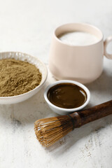 Bowl with hojicha green tea and chasen on light background