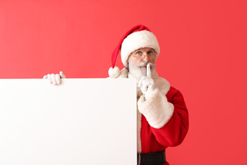 Santa Claus with blank poster showing silence gesture on color background