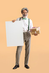 Stylish mature man with blank poster and gift boxes on color background