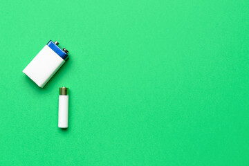 Alkaline batteries on green background, top view