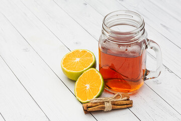 Black tea in a glass jar, lemon, cinnamon on a white wooden background. Copy space