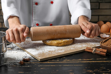 Confectioner rolling out gingerbread dough on table