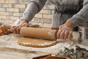 Woman rolling out gingerbread dough on table