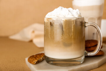 Glass cup of iced hojicha latte on beige background, closeup