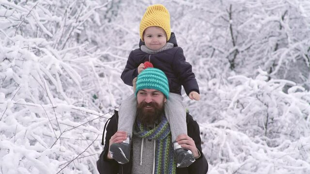 Winter father and son piggyback ride outdoor in snow forest. Dad play with child snow ball fight.