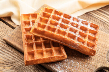 Board with delicious Belgian waffles on wooden background, closeup