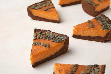 Pieces of delicious pumpkin pie on light background