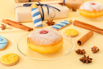 Cookies and sufganiyah for Hanukkah celebration with Christmas spices on color background