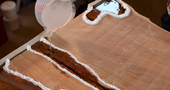 Top view carpenter pouring epoxy liquid in a wooden table
