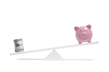 Roll dollar bills on scales outweighs piggy bank, concept saving and spending money.