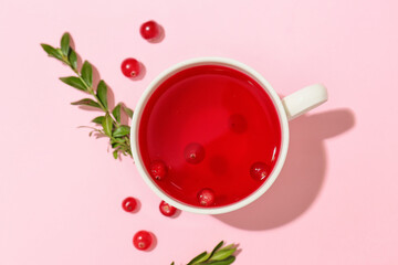 Cup of tasty lingonberry tea on pink background
