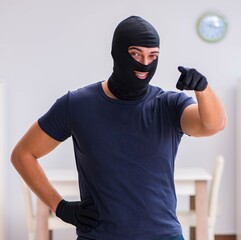 Robber wearing balaclava stealing valuable things