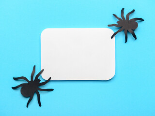 Blank paper sheet with spiders on blue background
