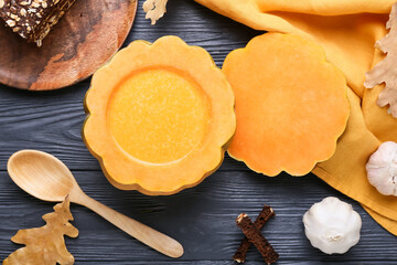 Tasty soup served in pumpkin on black wooden background