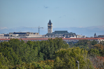 Fototapeta na wymiar Washington, DC, USA - October 27, 2021: Old Post Office Clock Tower Peaks Out Over the Trees with Yellowing Leaves as Seen from Arlington Ridge Park