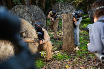 Teams of friends facing on battlefield in outdoor paintball arena