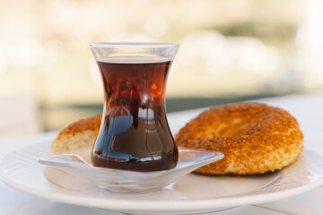 Crispy Turkish traditional bagel, simit with sesame and glass of turkish black tea, turkish breakfast pastry concept. Turkish tea in traditional glass cup. 