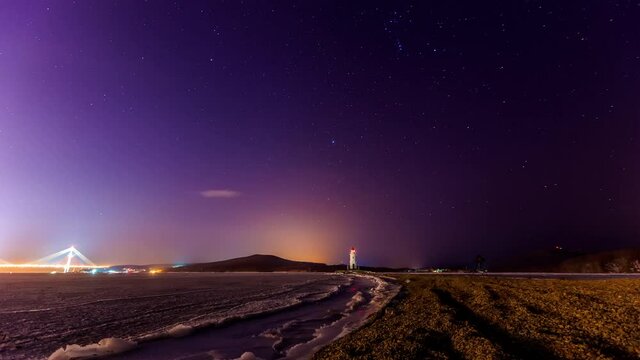 Tokarevsky lighthouse in Vladivostok. Time Laps. A picturesque lighthouse against the background of the starry sky. The Milky Way is moving around a beautiful old lighthouse.