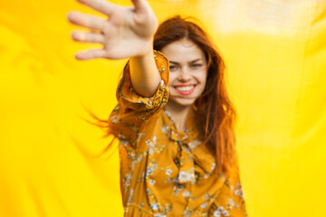 cheerful woman gesturing with her hands yellow background
