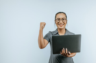 Portrait of Aan excited asian businesswoman glasses holding laptop computer and celebrating success isolated over background. Success and SME business concept.