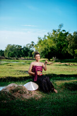 Naklejka na ściany i meble Young woman in beautiful Thai traditional clothes at rice field