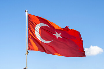 Turkish flag or flag of Turkey waving on flagpole against blue sky in Istanbul. Space for text.