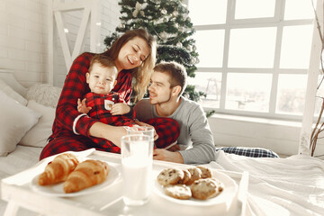 Beautiful family sitting on bed hugging and eating cookies