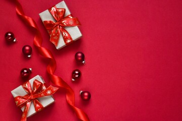 Flat lay Christmas gifts and balls and ribbon on red background. Copy space. New year, Christmas concept, greeting card. Top view.