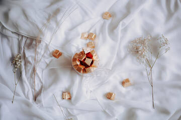 chocolates and candy in transparent bowl on white cloth with dried flower ornament