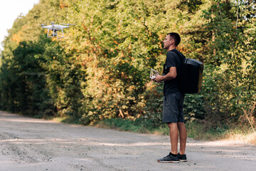 Fototapeta premium man flying a drone in road. Young Man navigating a flying drone