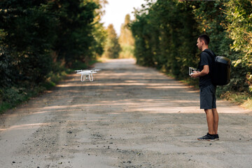 Fototapeta premium man flying a drone in road. Young Man navigating a flying drone