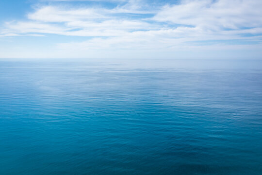 Closeup surface of calm ocean blue sea water with day light and clouds. Abstract Background Texture.