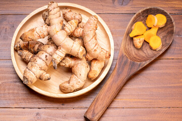 Turmeric root in wooden plate, Turmeric Thai herb on a wooden table background.