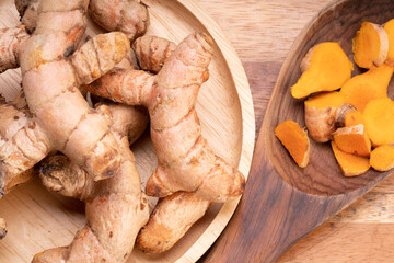 Turmeric root in wooden plate, Turmeric Thai herb on a wooden table background.