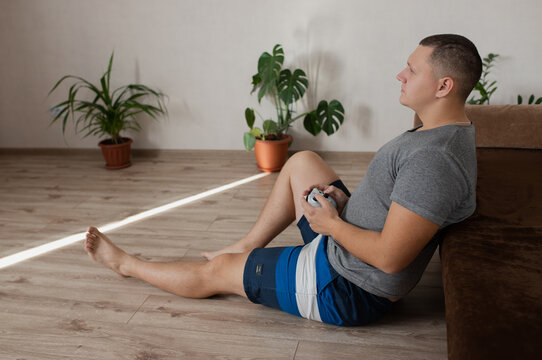 Russia, Barnaul, October 25, 2021: A man sits at home on the floor, holding a gamepad in his hands.