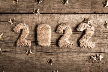 Numbers 2022 on a wooden background with sparkles of gold color top view. Festive postcard for Christmas and New Year.