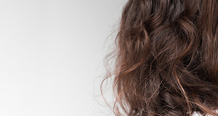 Back view of curly hair of brunette woman on gray plain background close-up. Banner mockup with copy space.