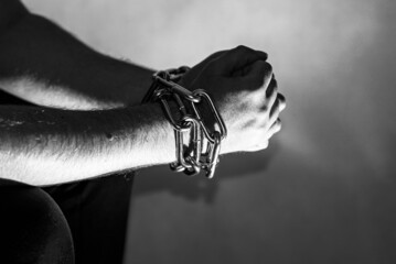 Chained chain hand sitting caucasian man prisoner,concept of imprisonment, punishment for offenders...