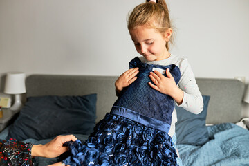 Mother and her daughter opening box with ordered dress. Online shopper customer holding dress