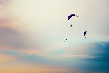 Paragliders flying in the sky. Paragliding in the cloudy colorful sky at sunset