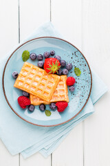 Fresh berry salad on blue dishes. Vintage wooden background.