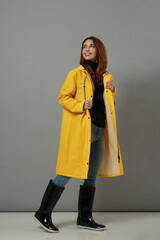 Happy caucasian girl in yellow raincoat and boots