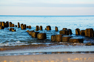 a sea wave beats against a breakwater on a sandy beach, long exposure