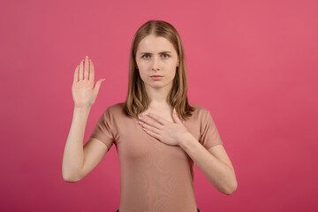 Young and attractive caucasian blonde girl holding her hand on her chest and open palm, making a...